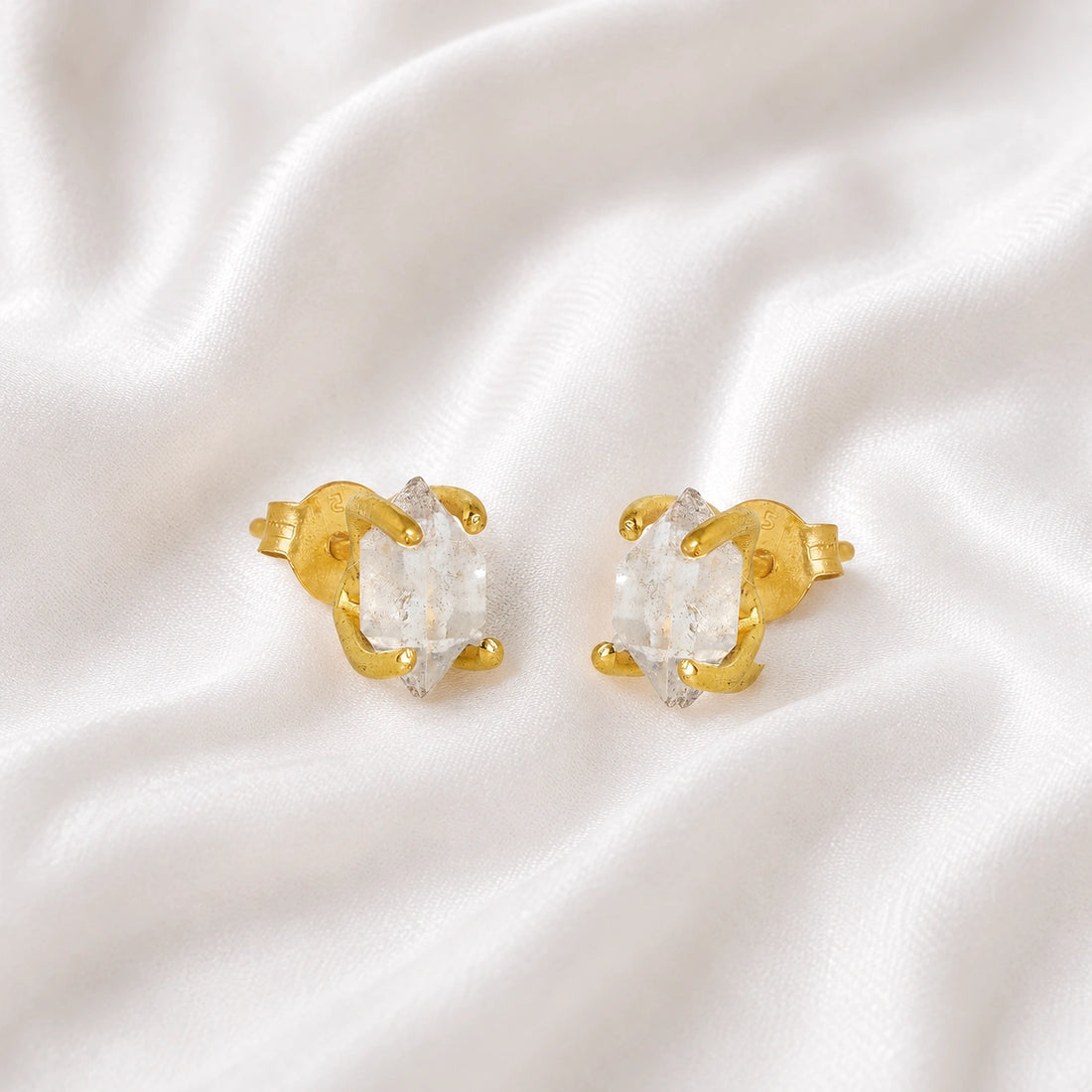 Crystal_earrings_in_gold_plated_silver_with_raw_herkimer_stone_at_slight_angle_view_on_soft_fabric_background
