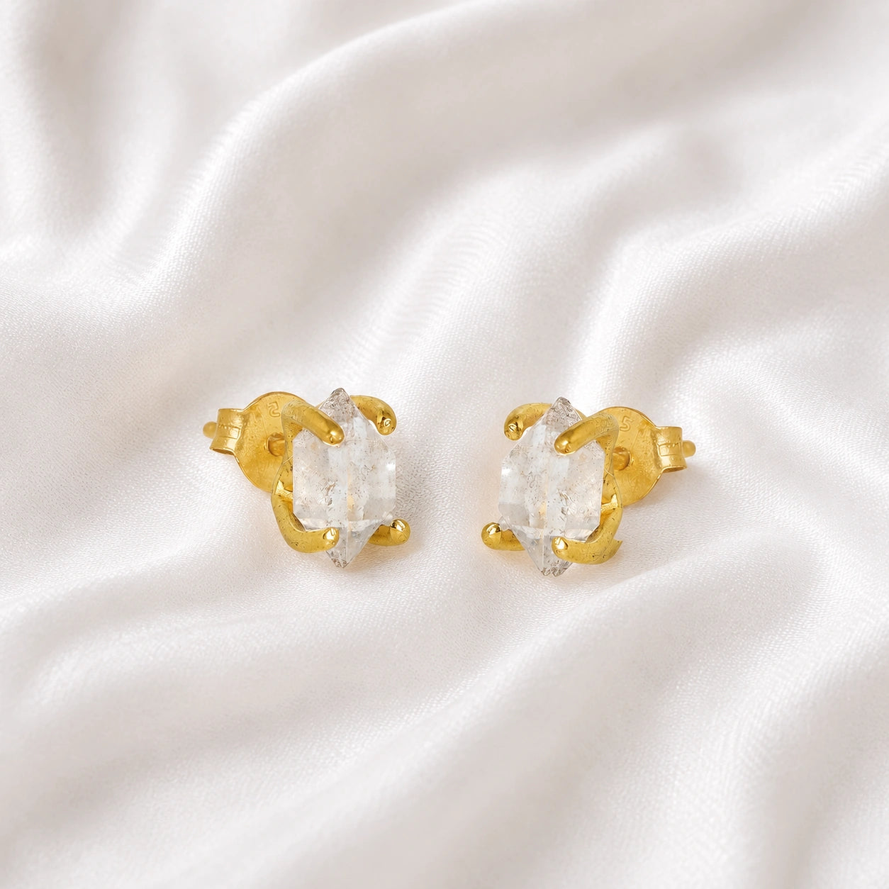 Crystal_earrings_in_gold_plated_silver_with_raw_herkimer_stone_at_slight_angle_view_on_soft_fabric_background