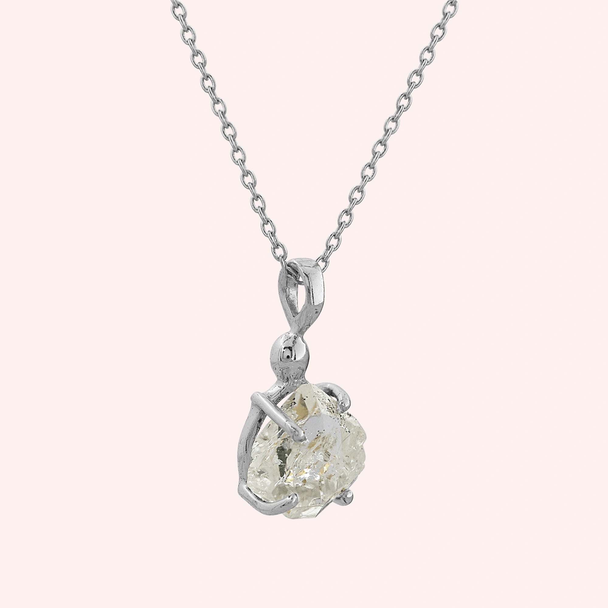 Crystal_necklace_in_sterling_silver_with_raw_stone_on_fine_chain_shown_in_slightly_angled_on_solid_pink_background