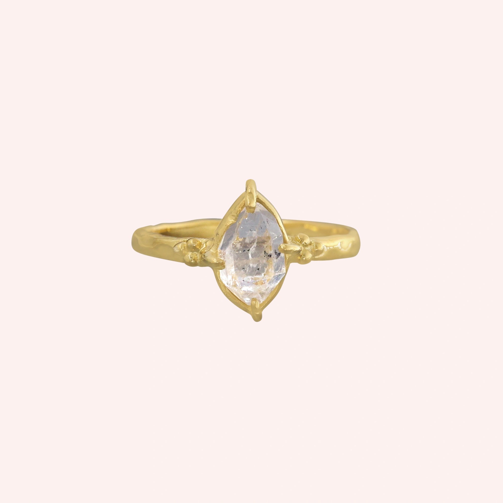 Crystal_ring_in_gold_plated_silver_with_raw_herkimer_stone_in_front_angle_view_on_solid_pink_background
