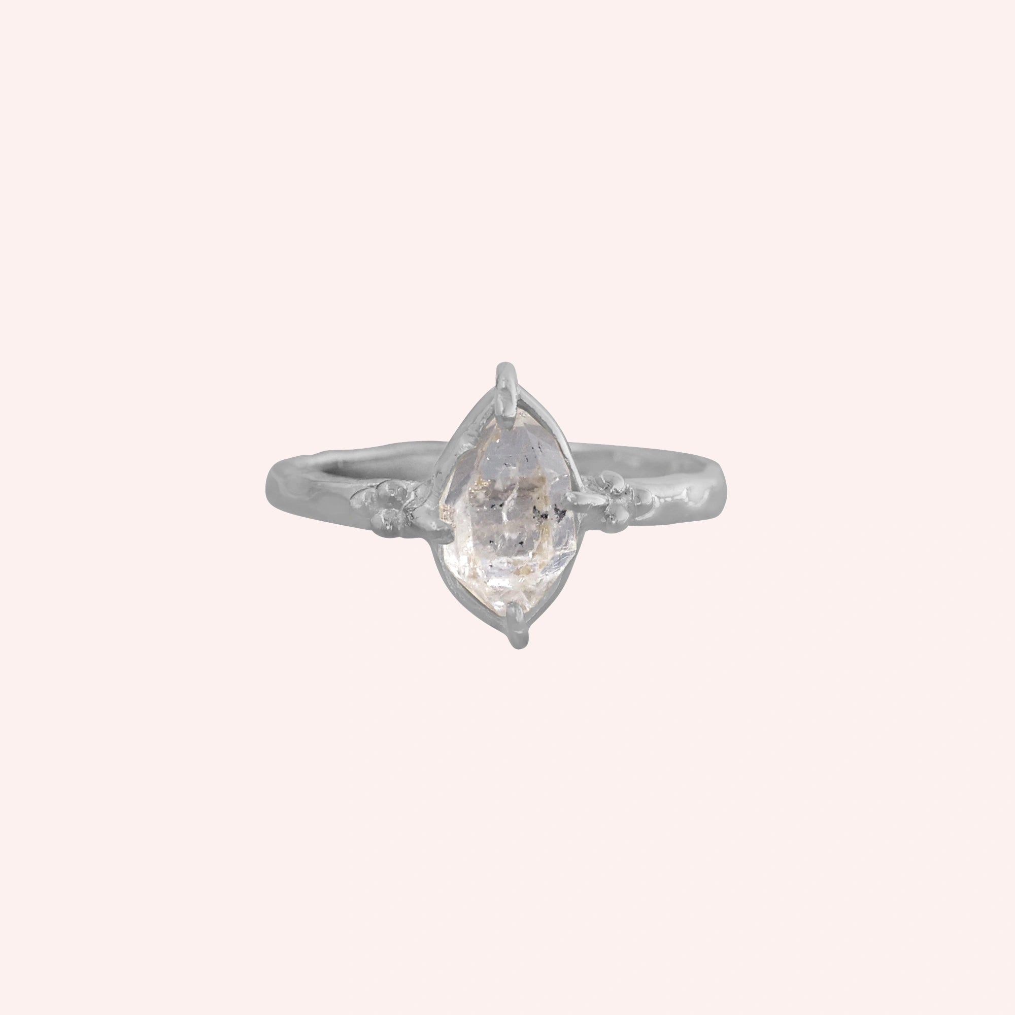 Crystal_ring_in_sterling_silver_with_raw_herkimer_stone_in_front_angle_view_on_solid_pink_background