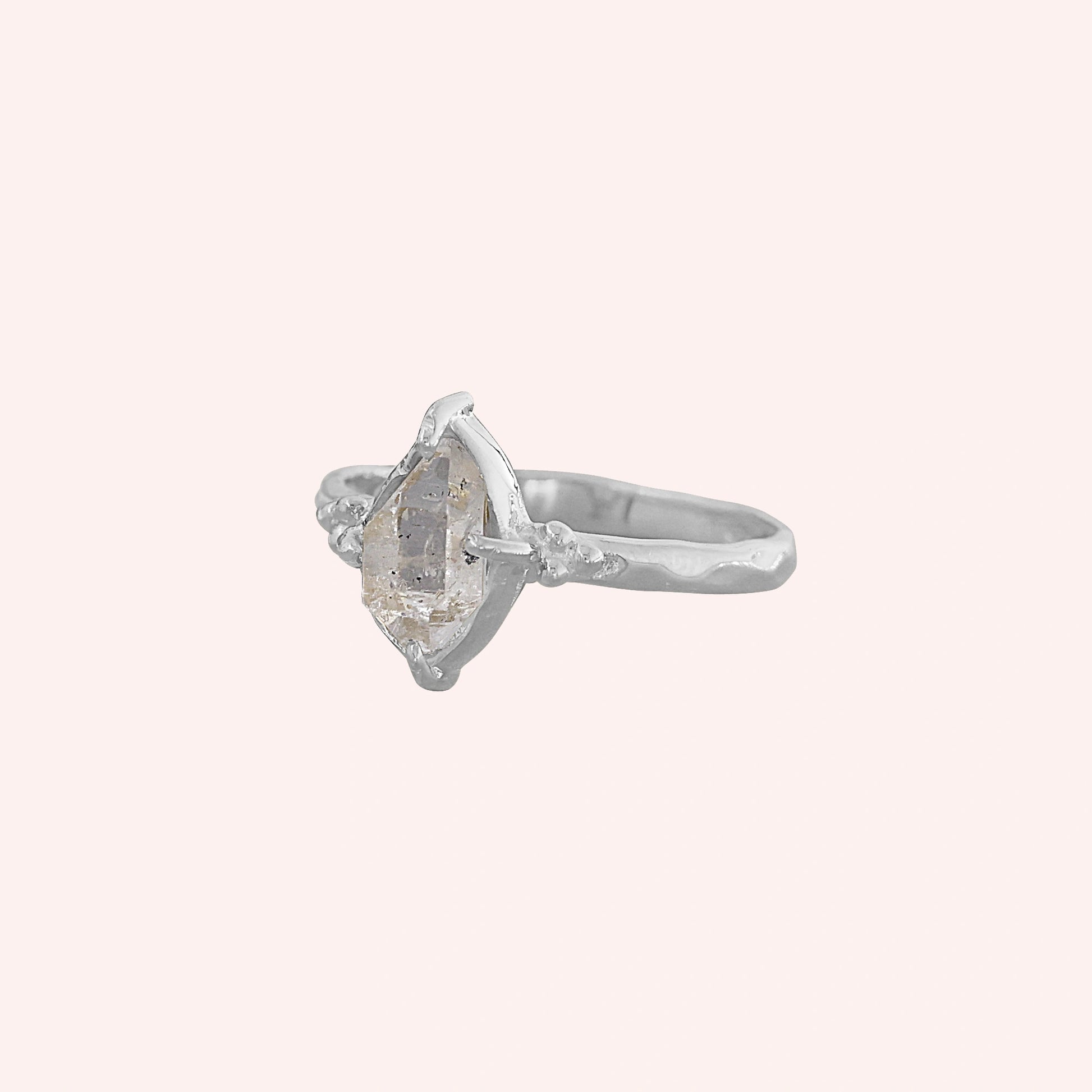 Crystal_ring_in_sterling_silver_with_raw_herkimer_stone_in_slightly_tilted_view_on_soft_fabric_background