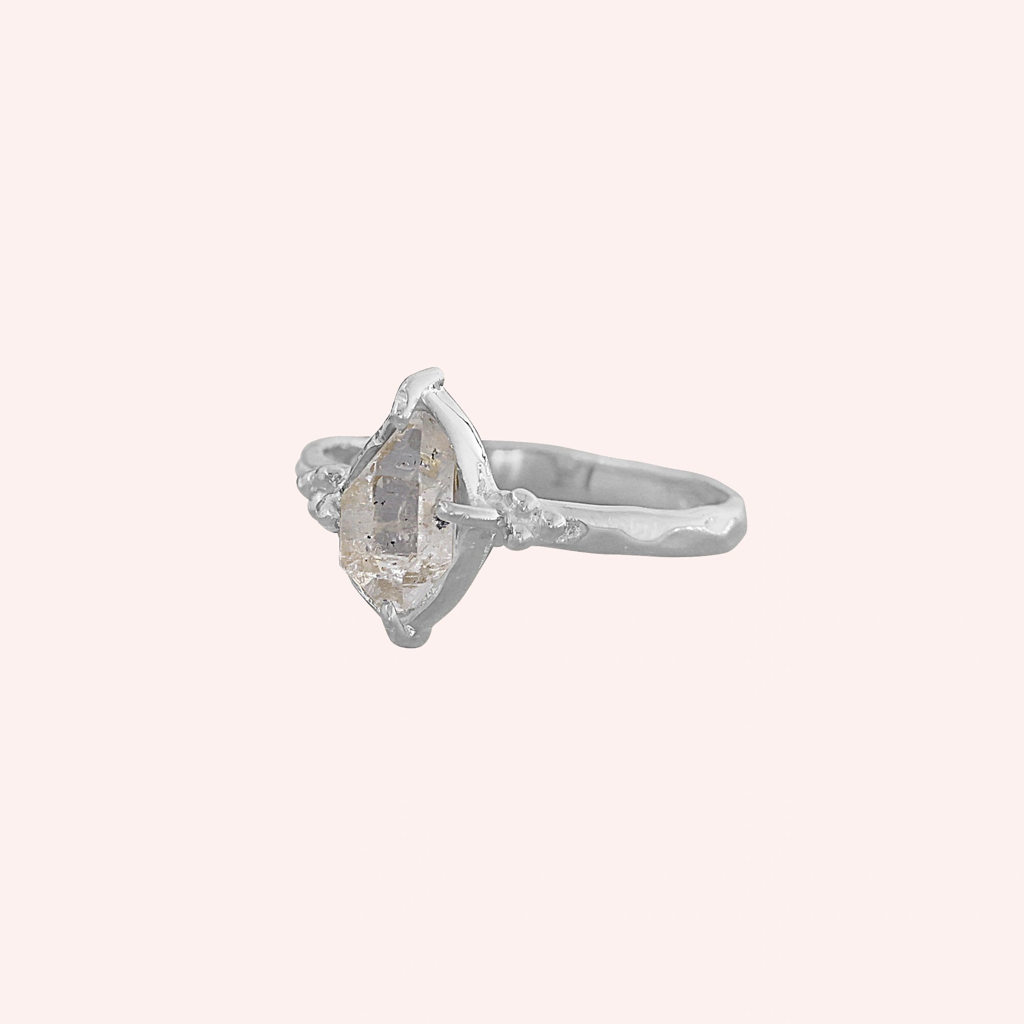Crystal_ring_in_sterling_silver_with_raw_herkimer_stone_in_slightly_tilted_view_on_soft_fabric_background