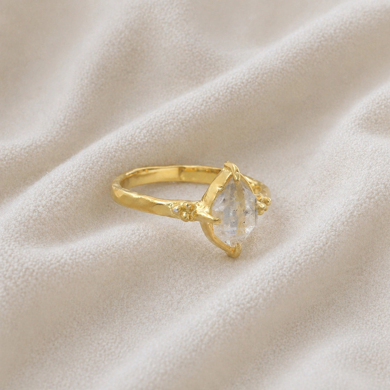 Crystal_ring_in_gold_plated_silver_with_raw_herkimer_stone_in_slight_tilted_view_on_soft_fabric_background