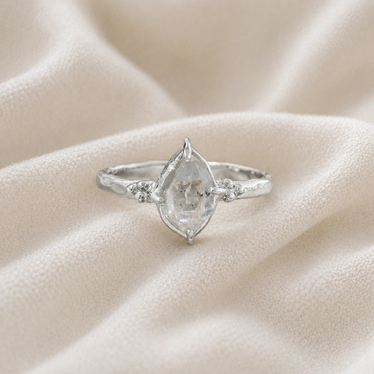 Crystal_ring_in_sterling_silver_with_raw_herkimer_stone_in_front_angle_view_on_soft_fabric_background