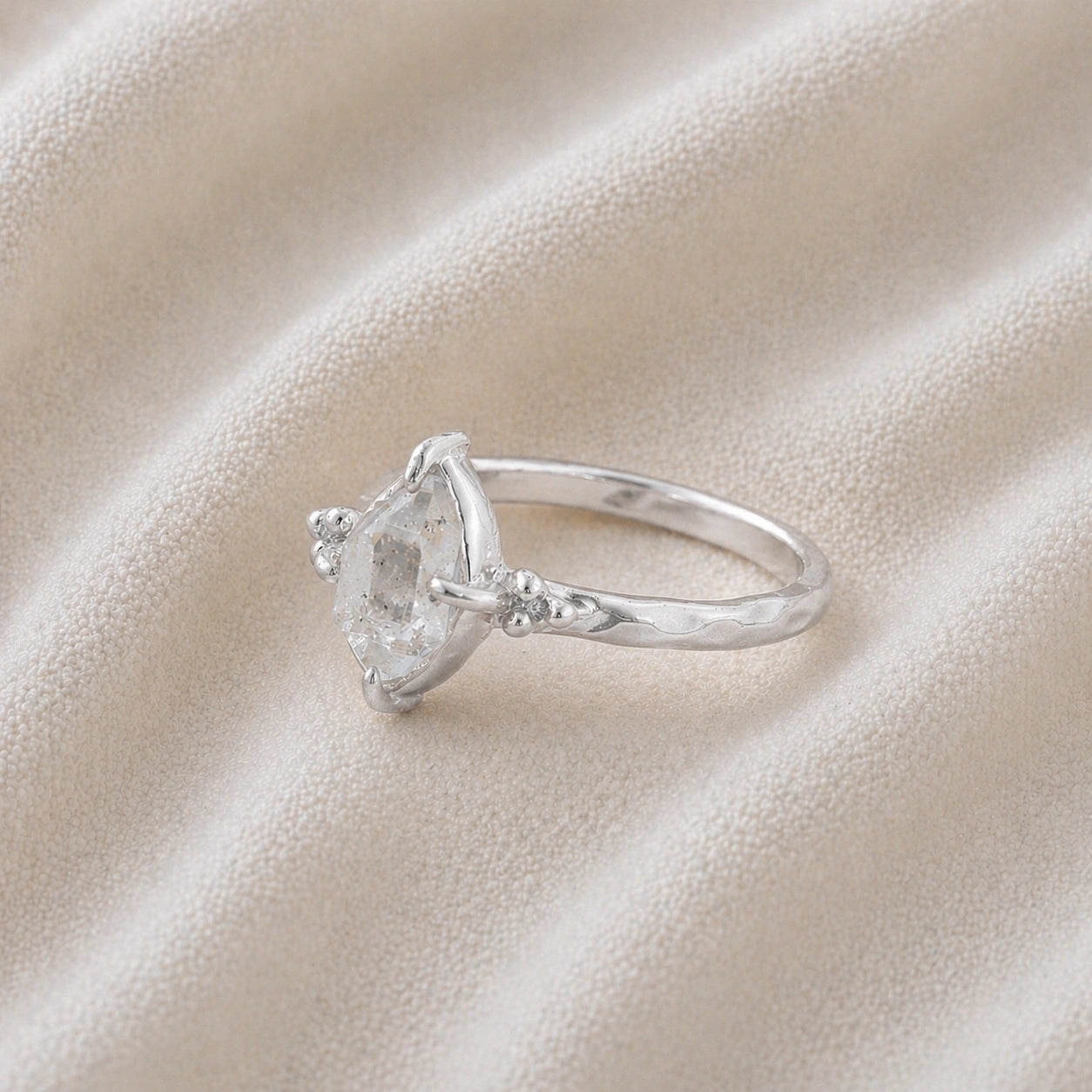 Crystal_ring_in_sterling_silver_with_raw_herkimer_stone_in_slightly_tilted_view_on_soft_fabric_background