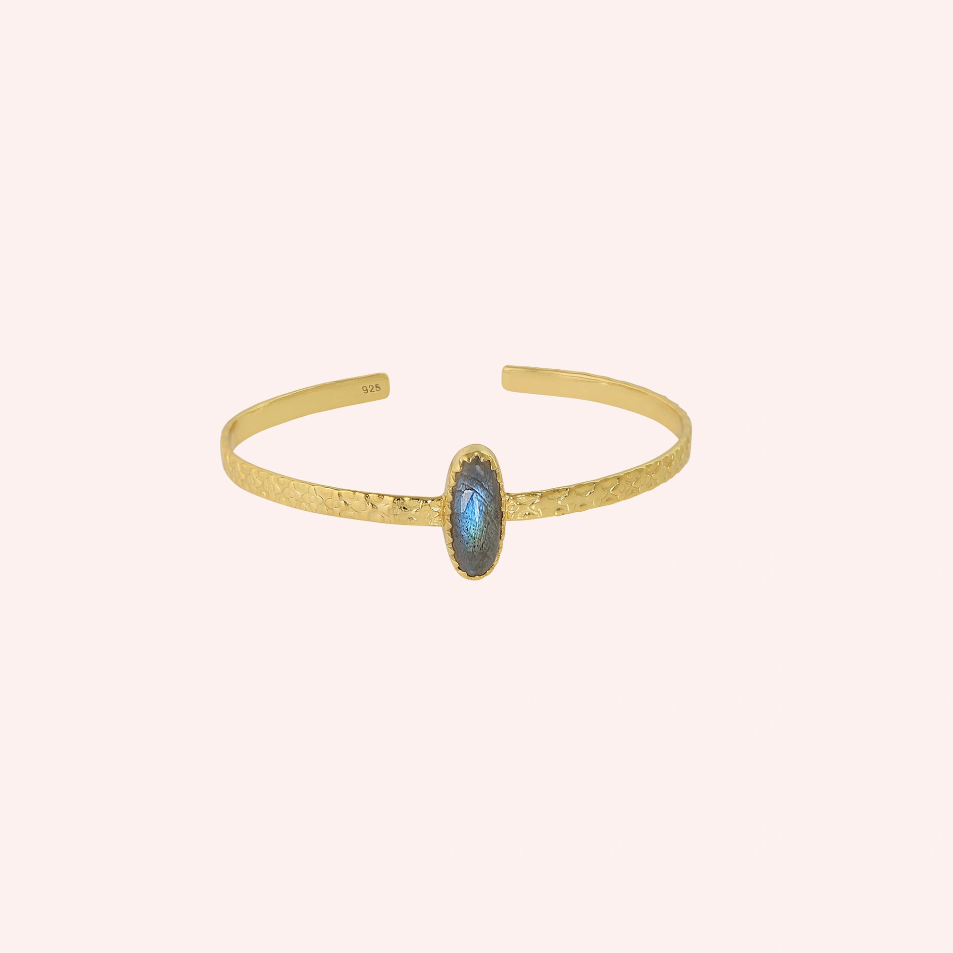 Cuff_bracelet_in_gold_plated_silver_with_an_oval_labradorite_stone_at_front_angle_view_on_solid_pink_background