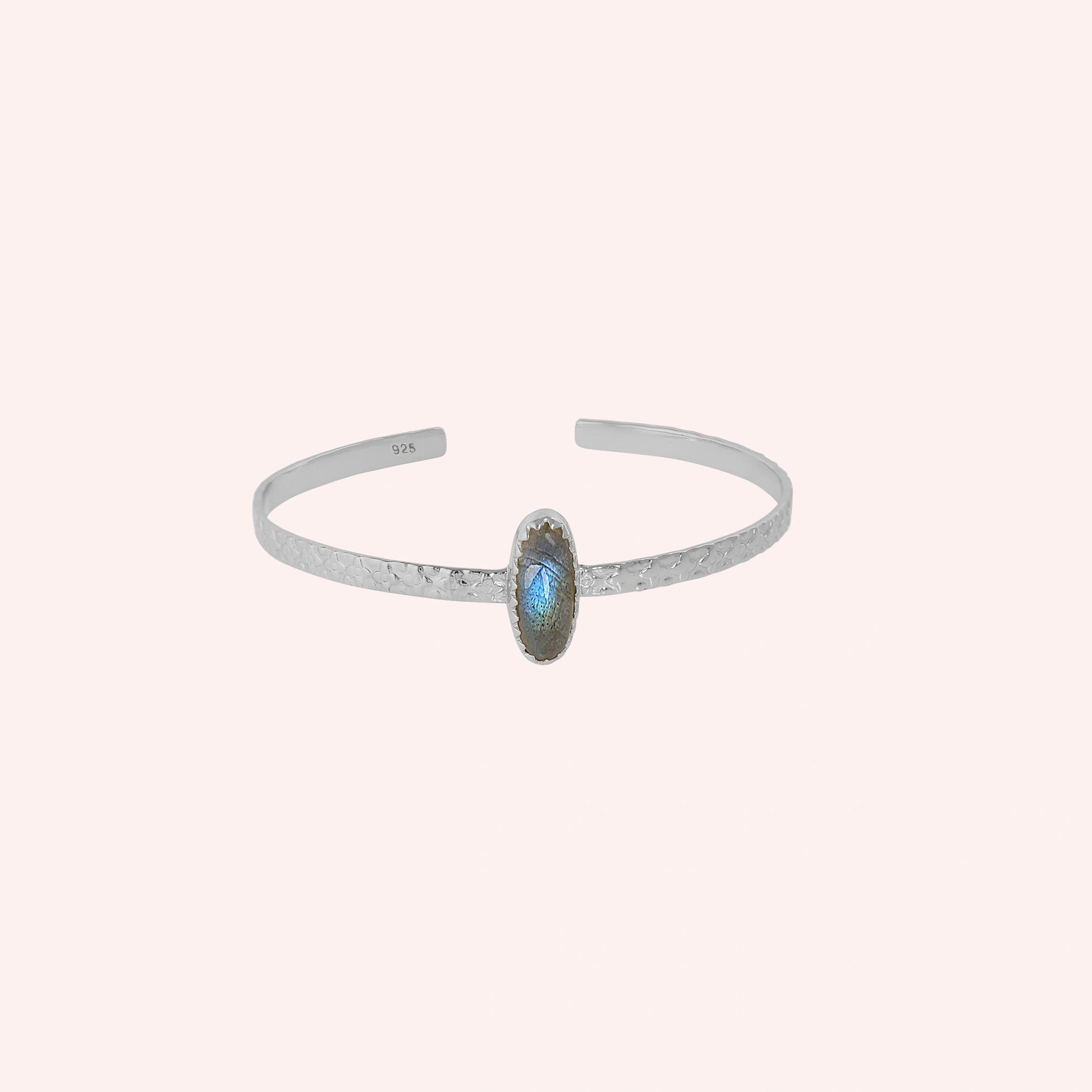 Cuff_bracelet_in_sterling_silver_with_an_oval_labradorite_stone_at_front_angle_view_on_solid_pink_background