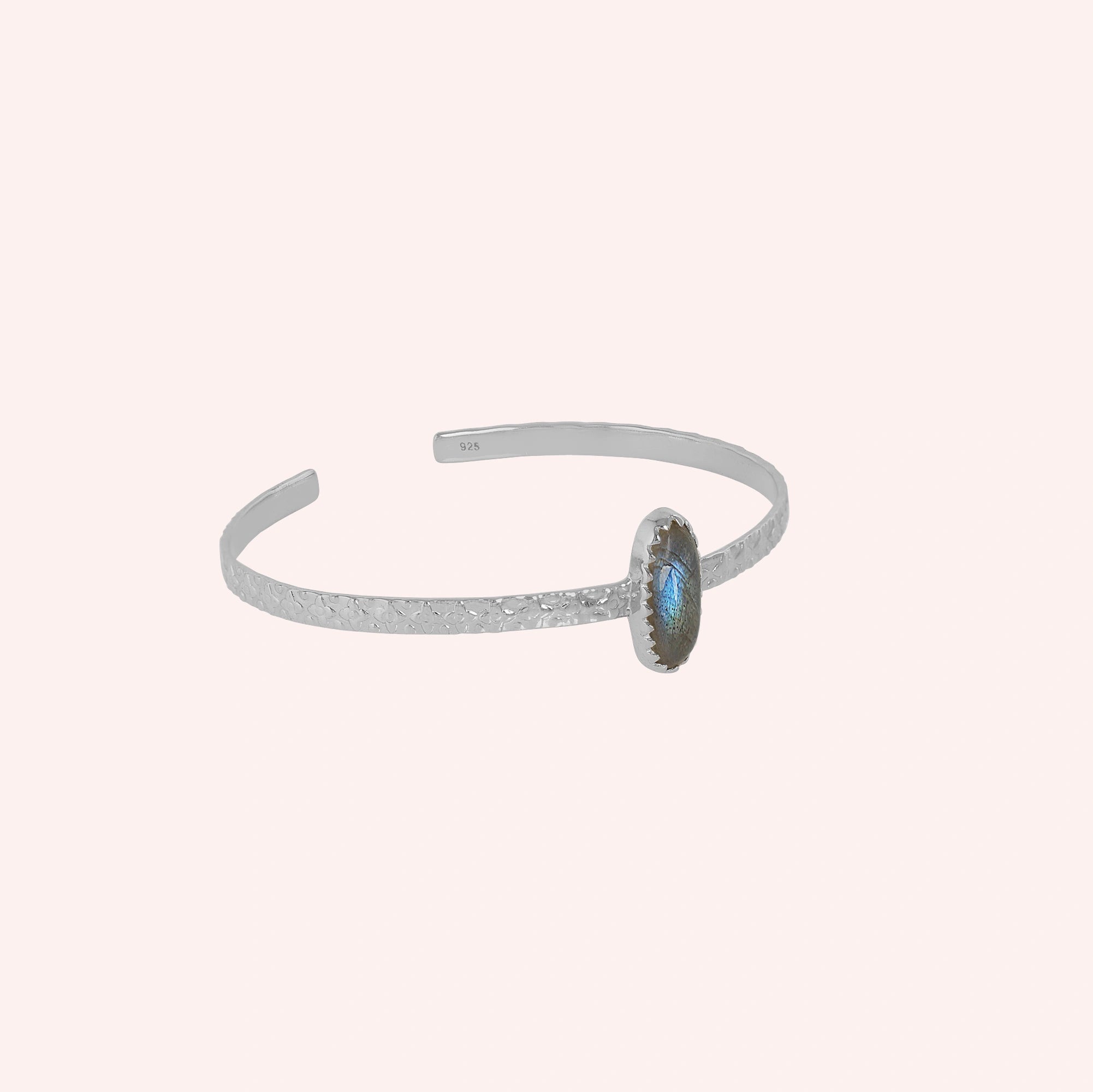 Cuff_bracelet_in_sterling_silver_with_an_oval_labradorite_stone_at_slight_angle_view_on_solid_pink_background