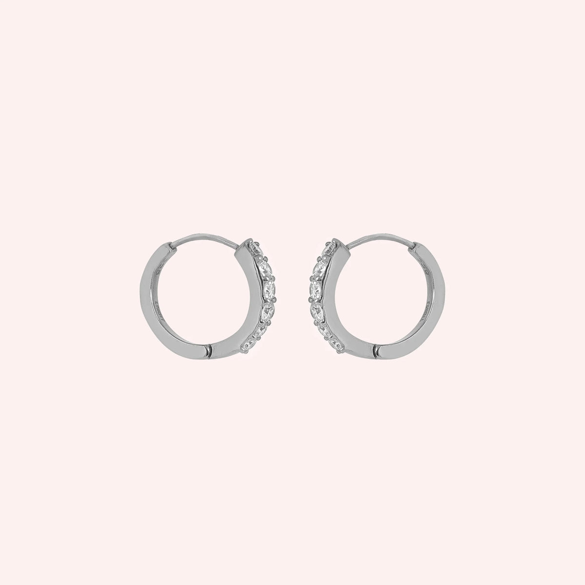 Cute_earrings_in_sterling_silver_with_CZ_stones_at_side_angle_view_on_solid_pink_background