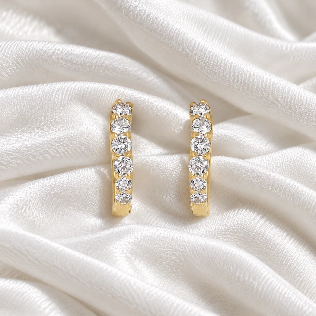 Cute_earrings_in_gold_plated_silver_with_CZ_stones_at_front_angle_view_on_soft_fabric_background