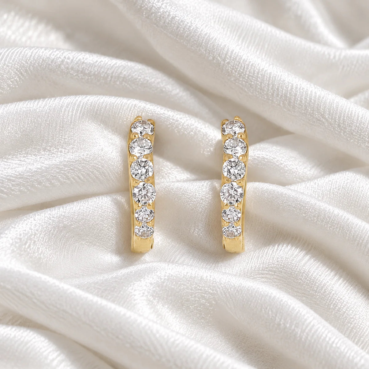 Cute_earrings_in_gold_plated_silver_with_CZ_stones_at_front_angle_view_on_soft_fabric_background