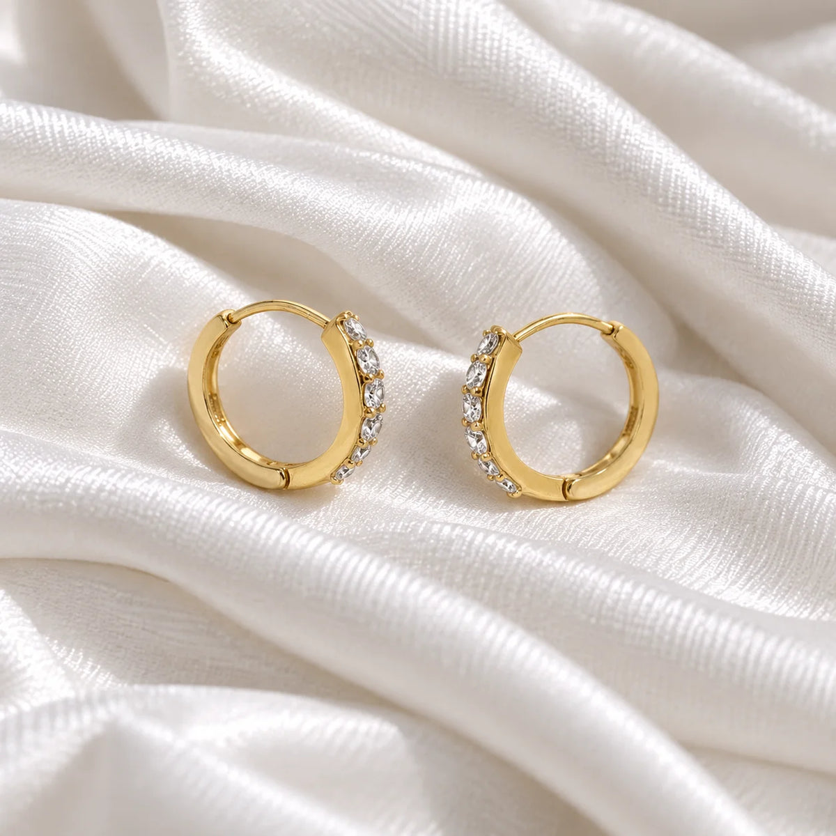 Cute_earrings_in_gold_plated_silver_with_CZ_stones_at_side_angle_view_on_soft_fabric_background