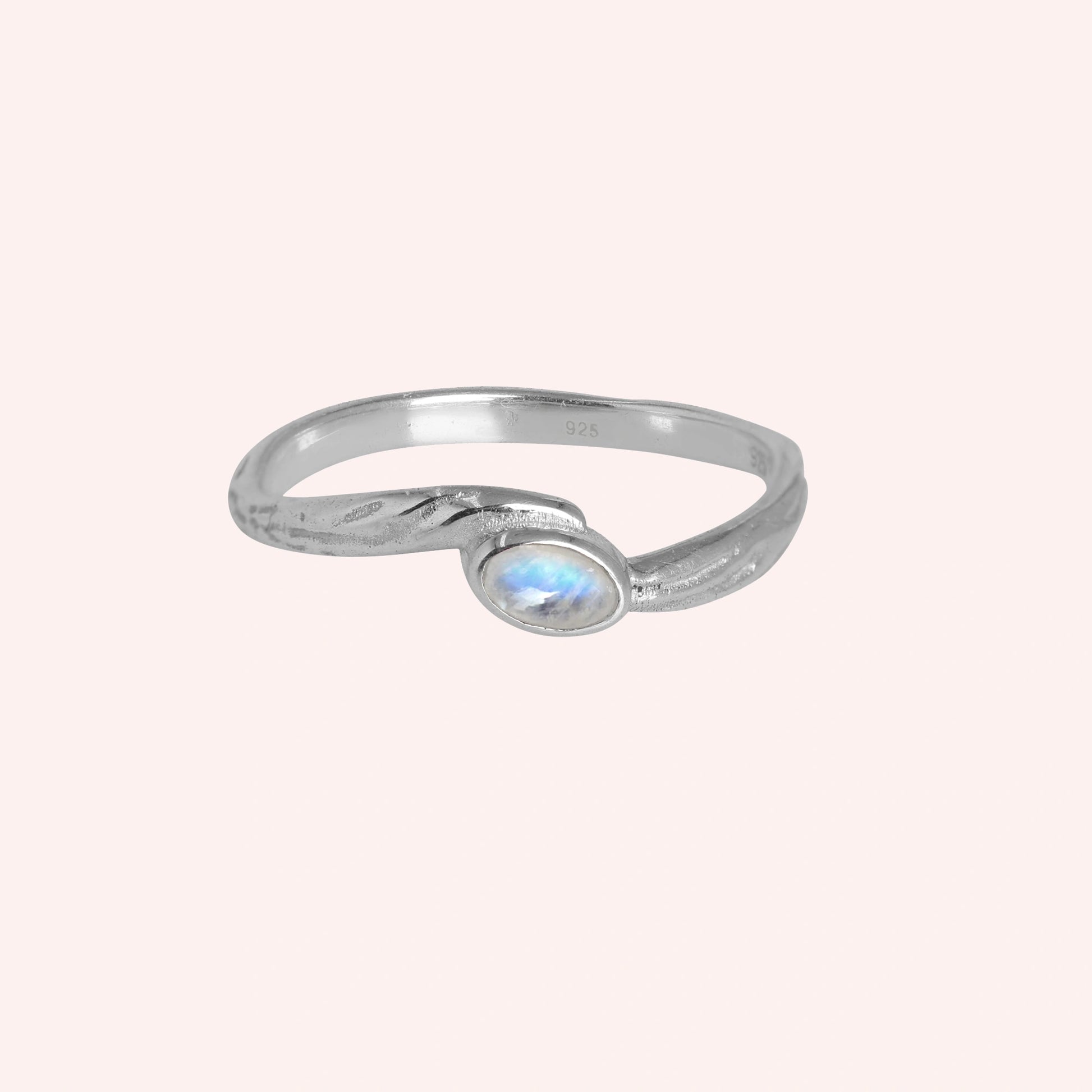 Cute_ring_sterling_silver_with_oval_moonstone_and_textured_wave_band_shown_at_front_angle_on_solid_pink_background