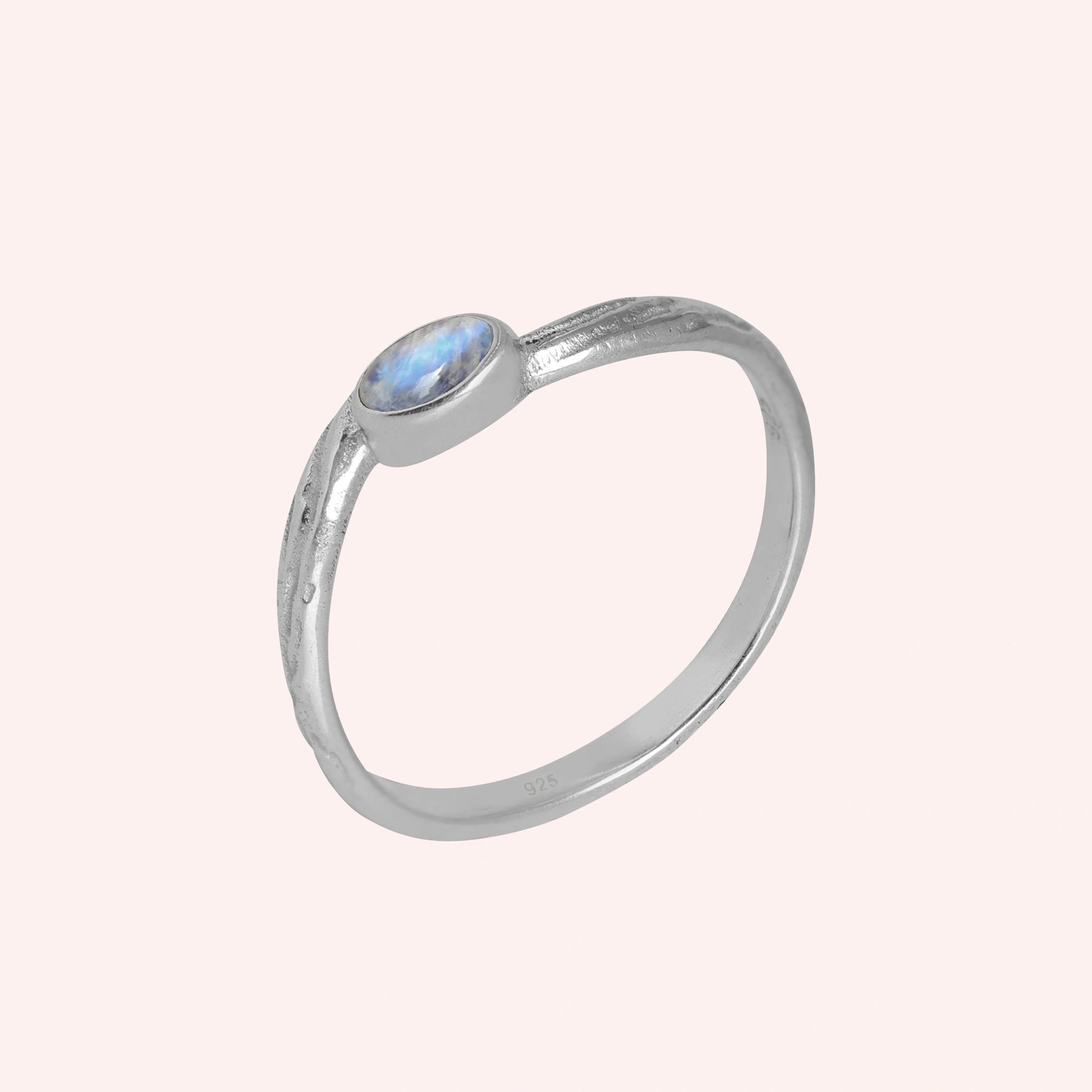 Cute_ring_sterling_silver_with_oval_moonstone_and_textured_wave_band_shown_slightly_tilted_on_solid_pink_background