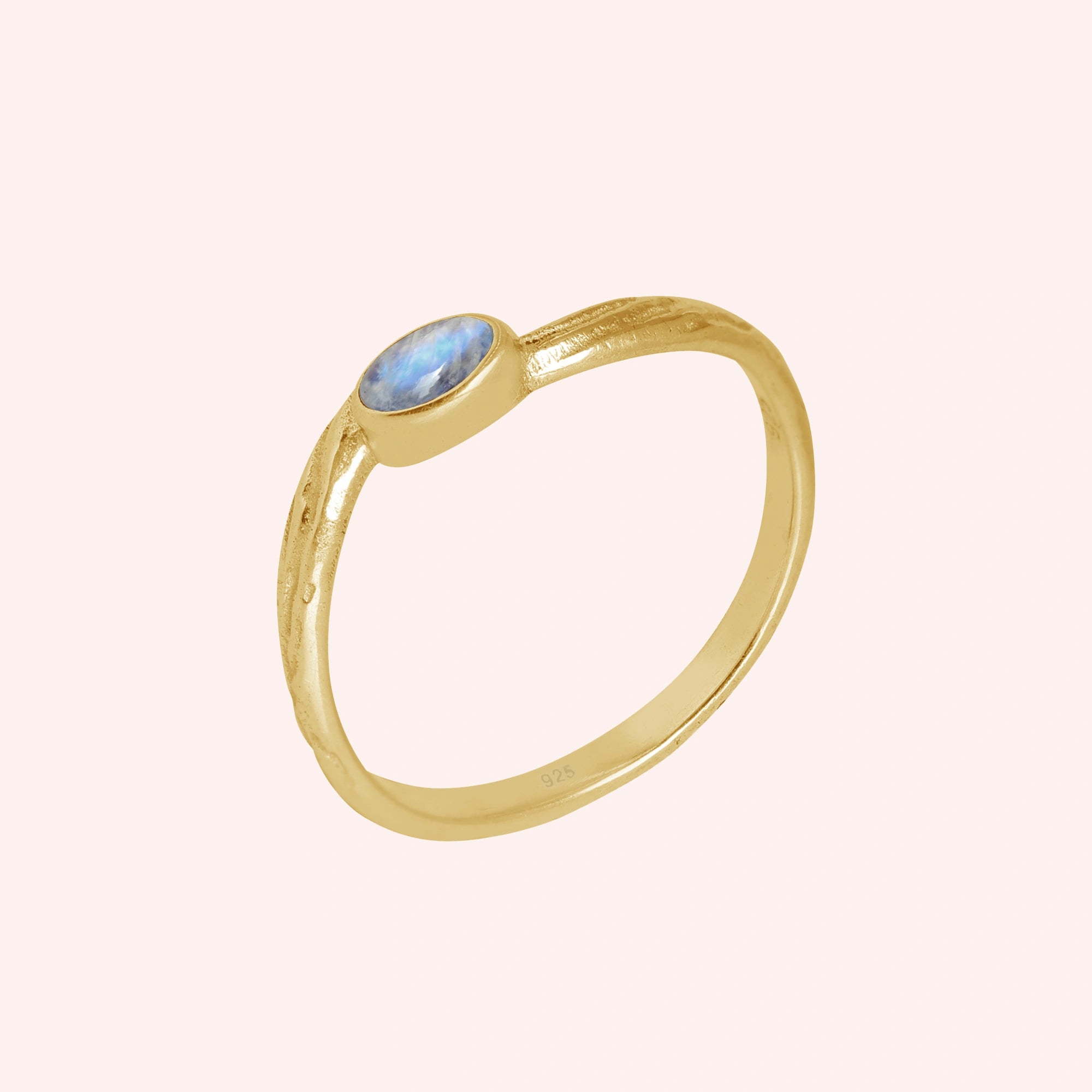 Cute_ring_gold_plated_silver_with_oval_moonstone_and_textured_wave_band_shown_slightly_tilted_on_solid_pink_background
