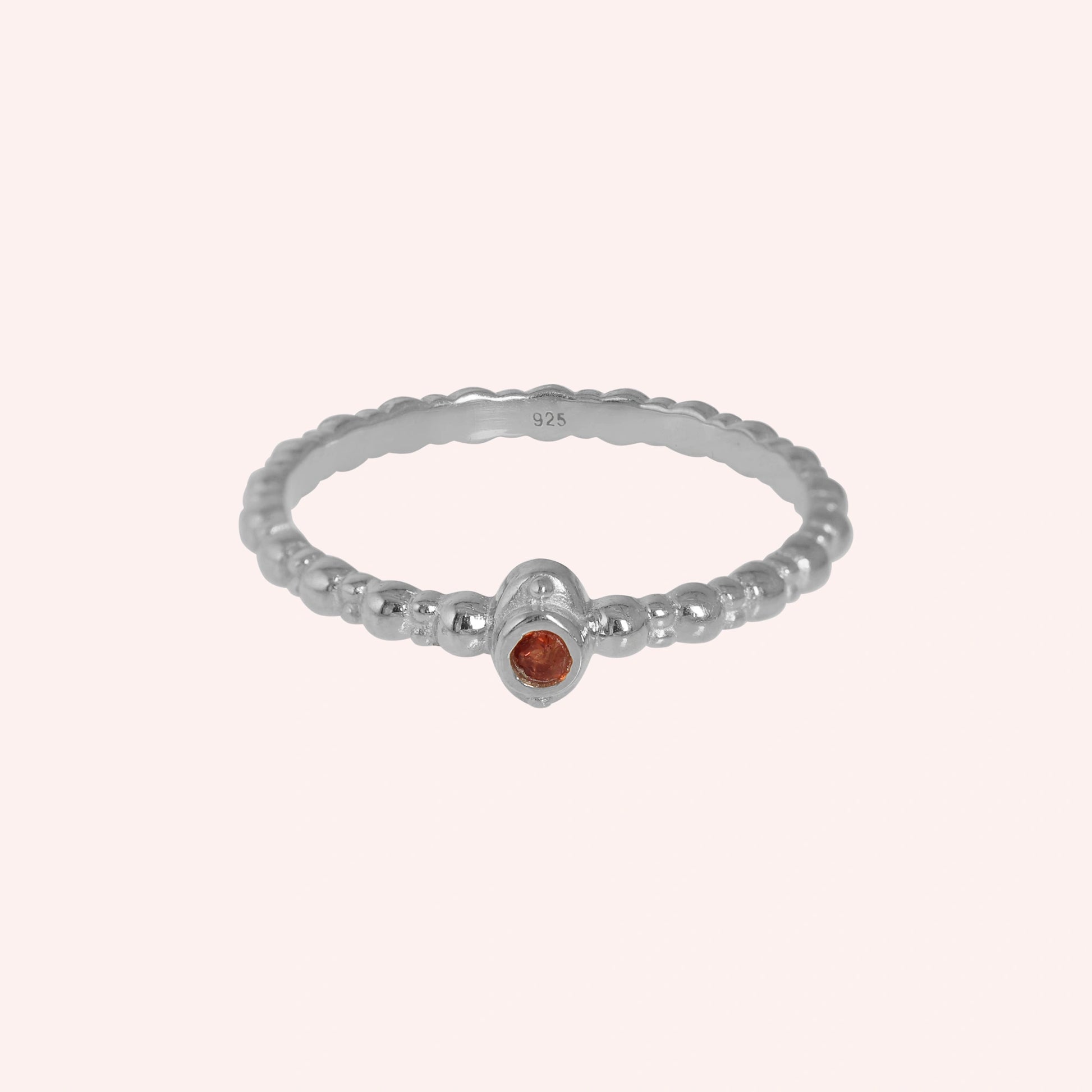 Dainty-ring-with-red-garnet-gemstone-sterling-silver-front-view-on-soft-pink-background