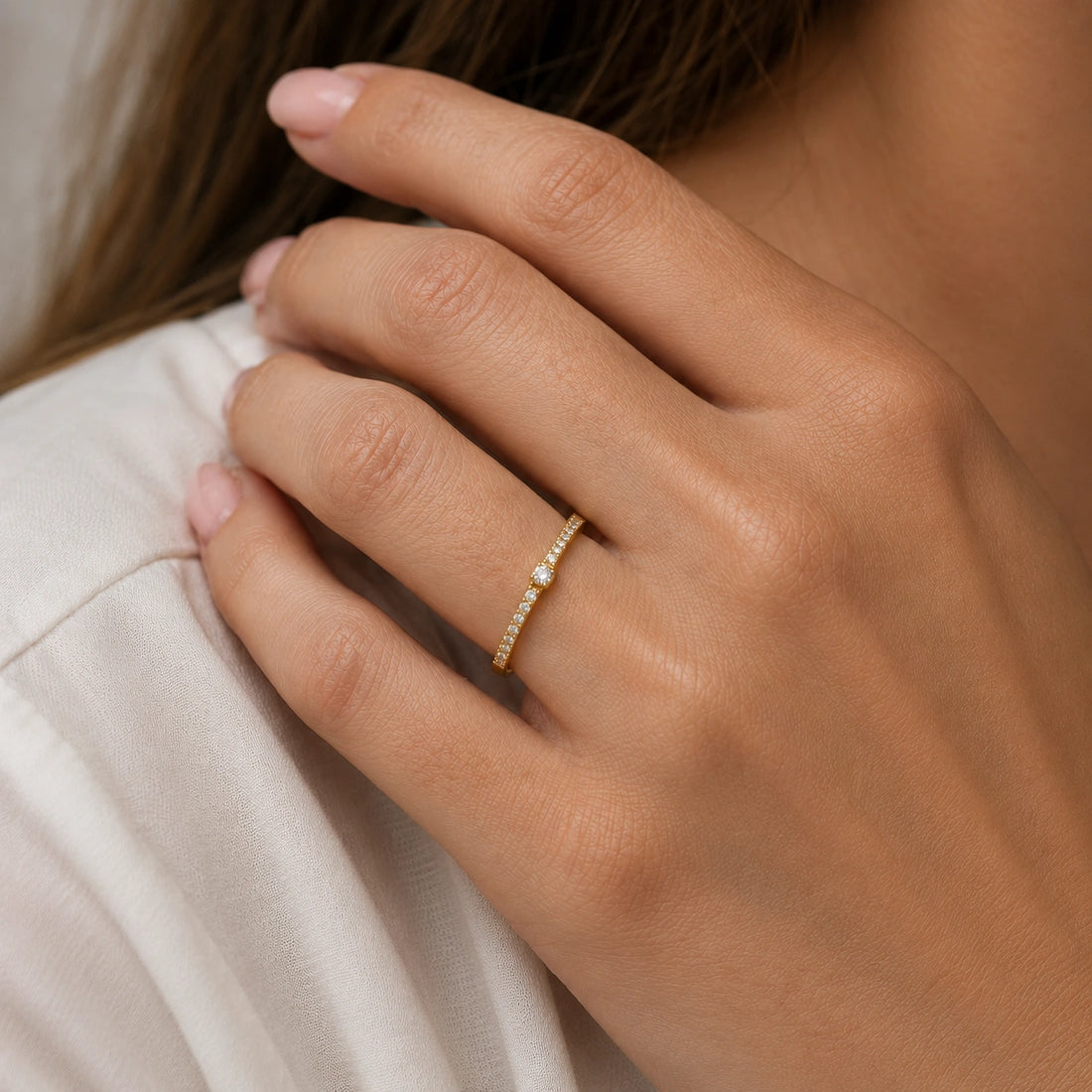 Dainty_ring_in_gold_plated_silver_at_slight_angle_featuring_diamonds_on_soft_fabric_background
