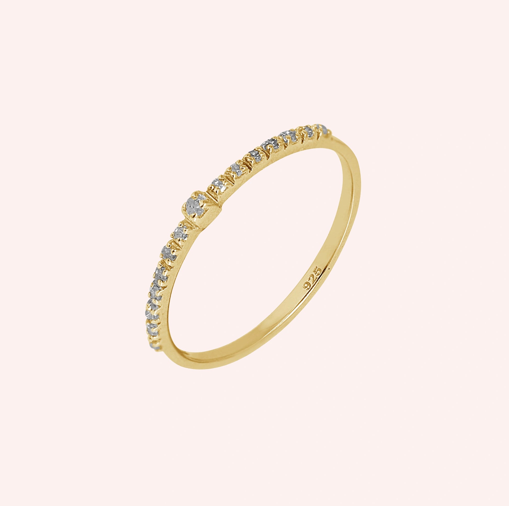 Dainty_ring_in_gold_plated_silver_at_front_angle_featuring_diamonds_on_solid_pink_background