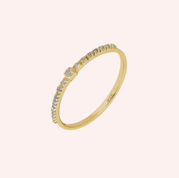 Dainty_ring_in_gold_plated_silver_at_front_angle_featuring_diamonds_on_solid_pink_background