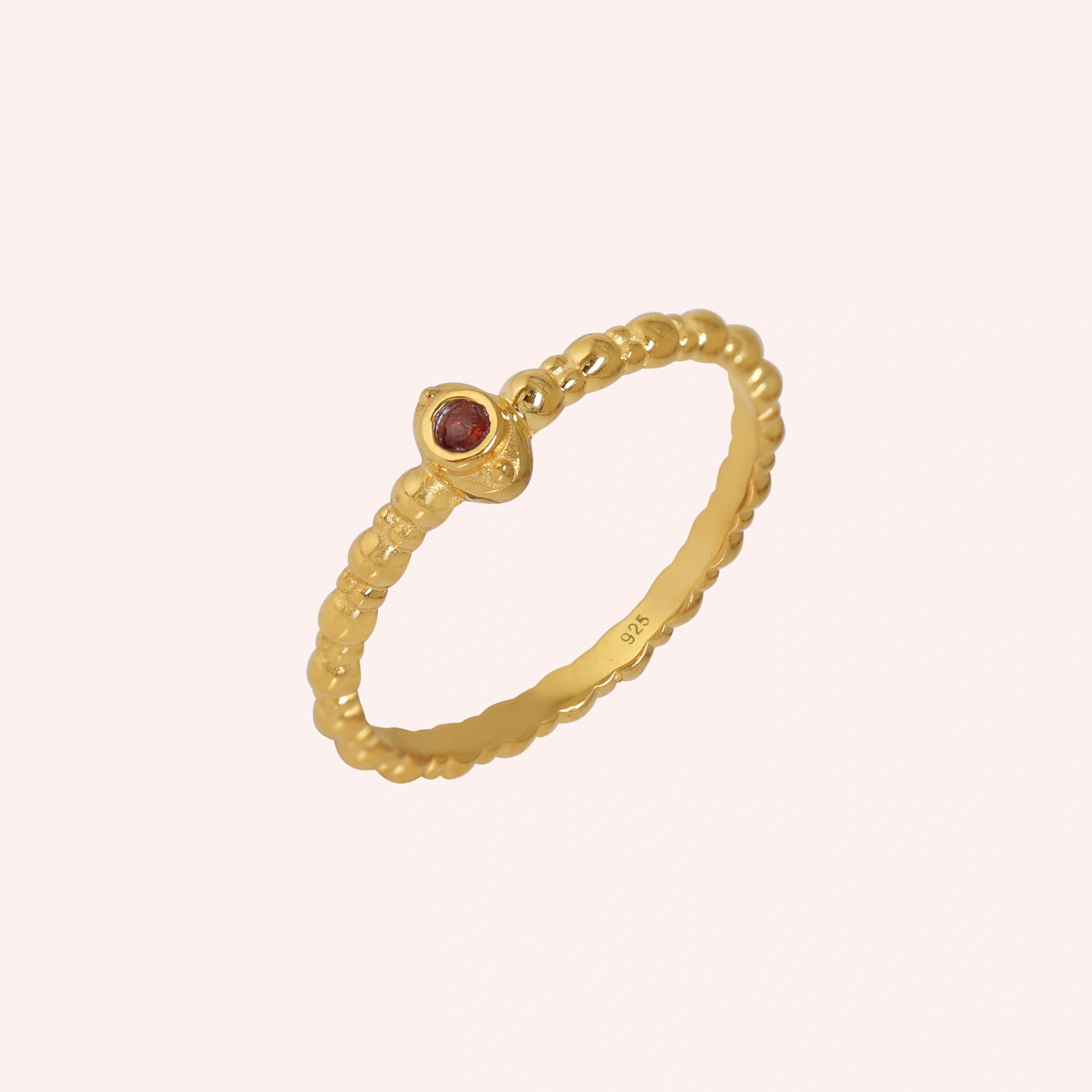 Dainty-ring-with-red-garnet-gemstone-gold-plated-silver-angled-view-on-soft-pink-background