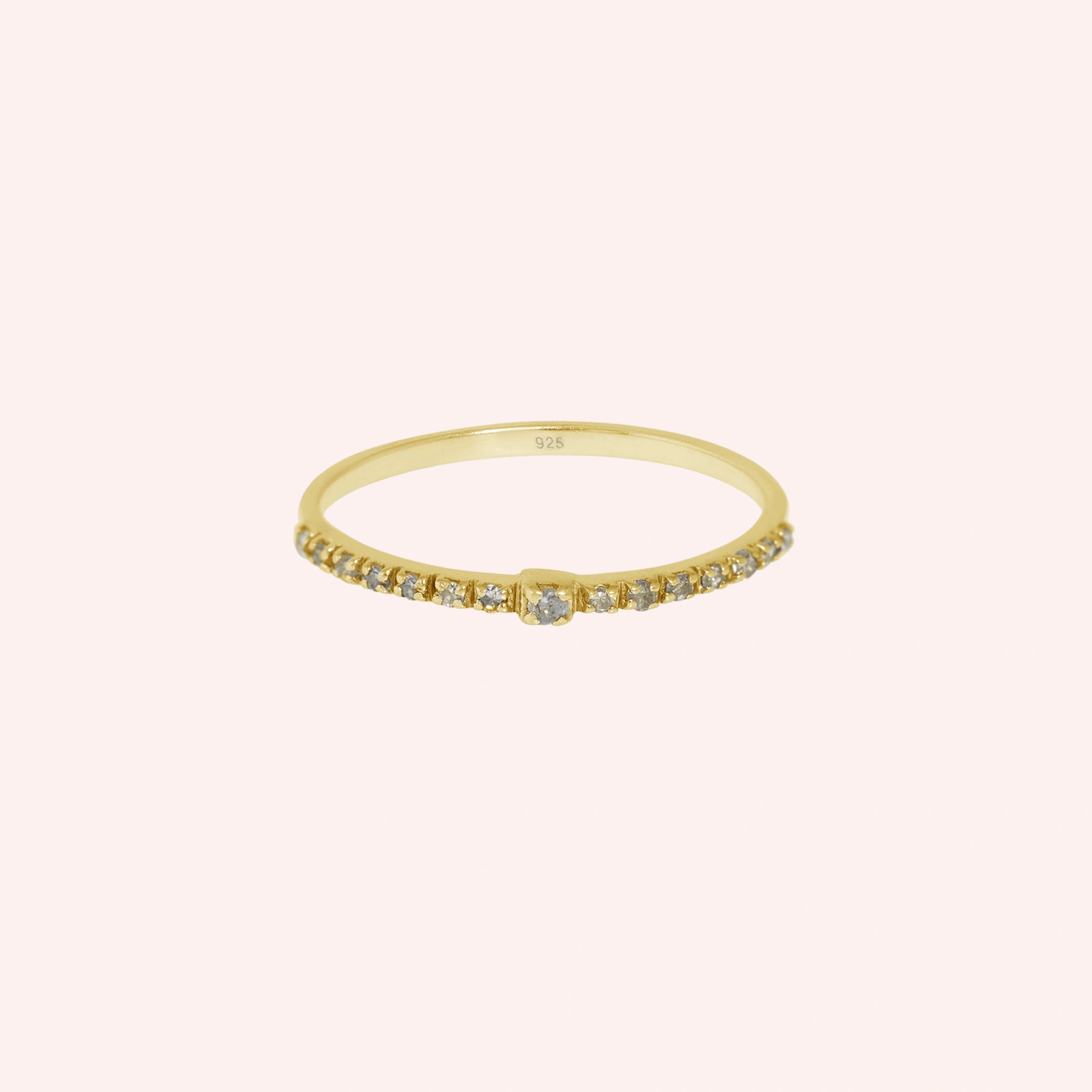 Dainty_ring_in_gold_plated_silver_at_front_angle_featuring_diamonds_on_solid_pink_background