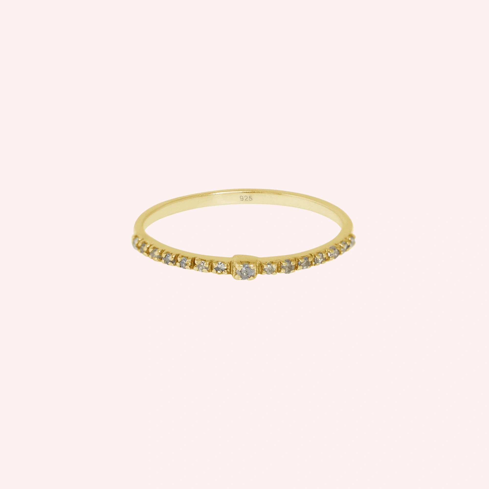 Dainty_ring_in_gold_plated_silver_at_front_angle_featuring_diamonds_on_solid_pink_background