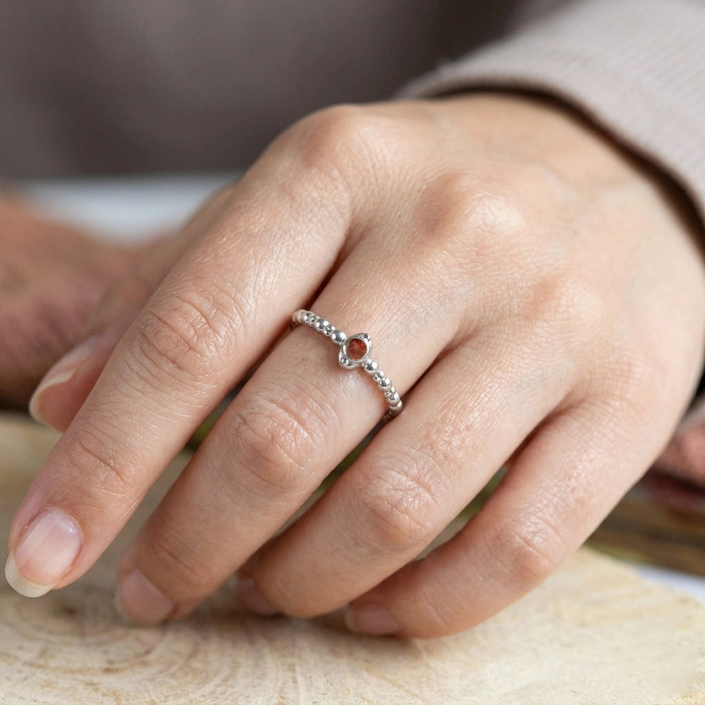 Dainty-ring-with-red-garnet-gemstone-gold-plated-silver-angled-view-on-white-satin-background