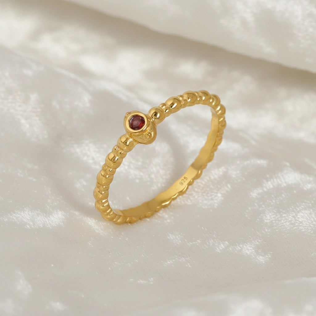 Dainty-ring-with-red-garnet-gemstone-gold-plated-silver-angled-view-on-white-satin-background