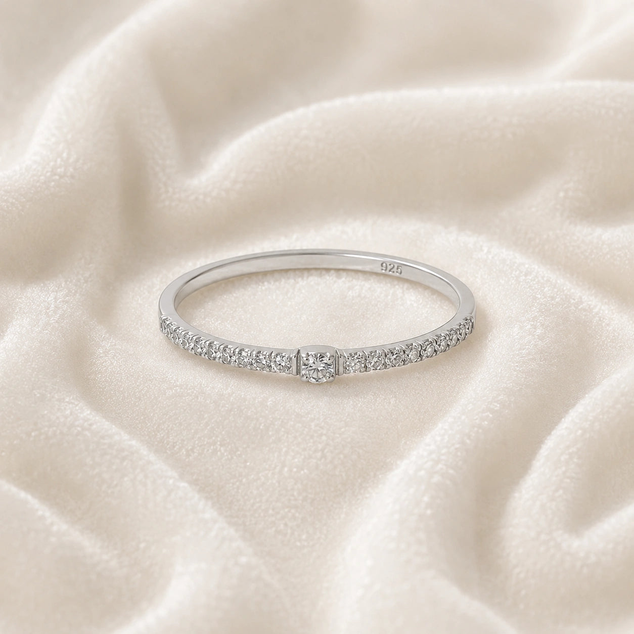 Dainty_ring_in_sterling_silver_at_front_angle_featuring_diamonds_on_soft_fabric_background