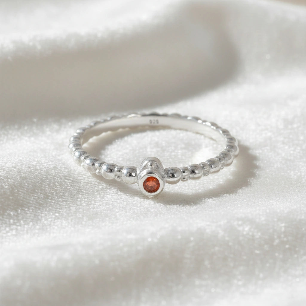 Dainty-ring-with-red-garnet-gemstone-sterling-silver-front-view-on-white-satin-background