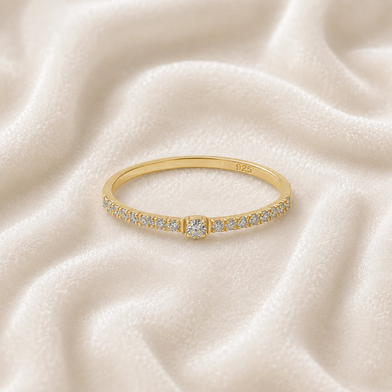 Dainty_ring_in_gold_plated_silver_at_front_angle_featuring_diamonds_on_soft_fabric_background