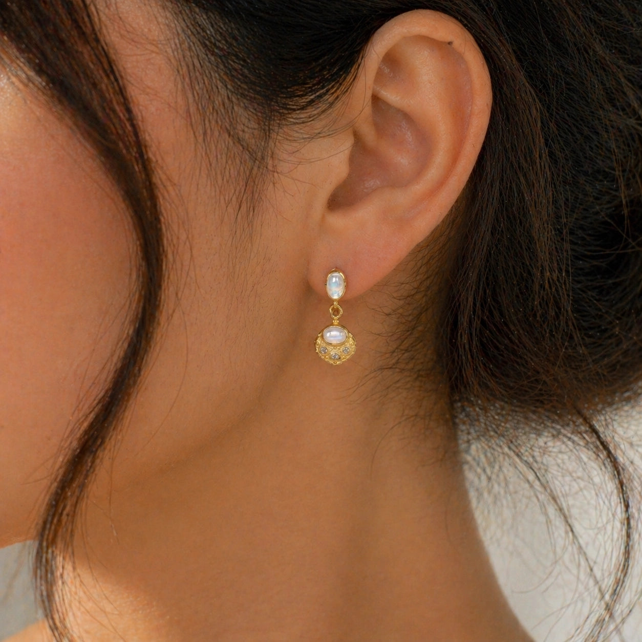 Dangle_earrings_in_gold_plated_silver_with_moonstone_and_labradorite_worn_by_a_model_in_natural_light