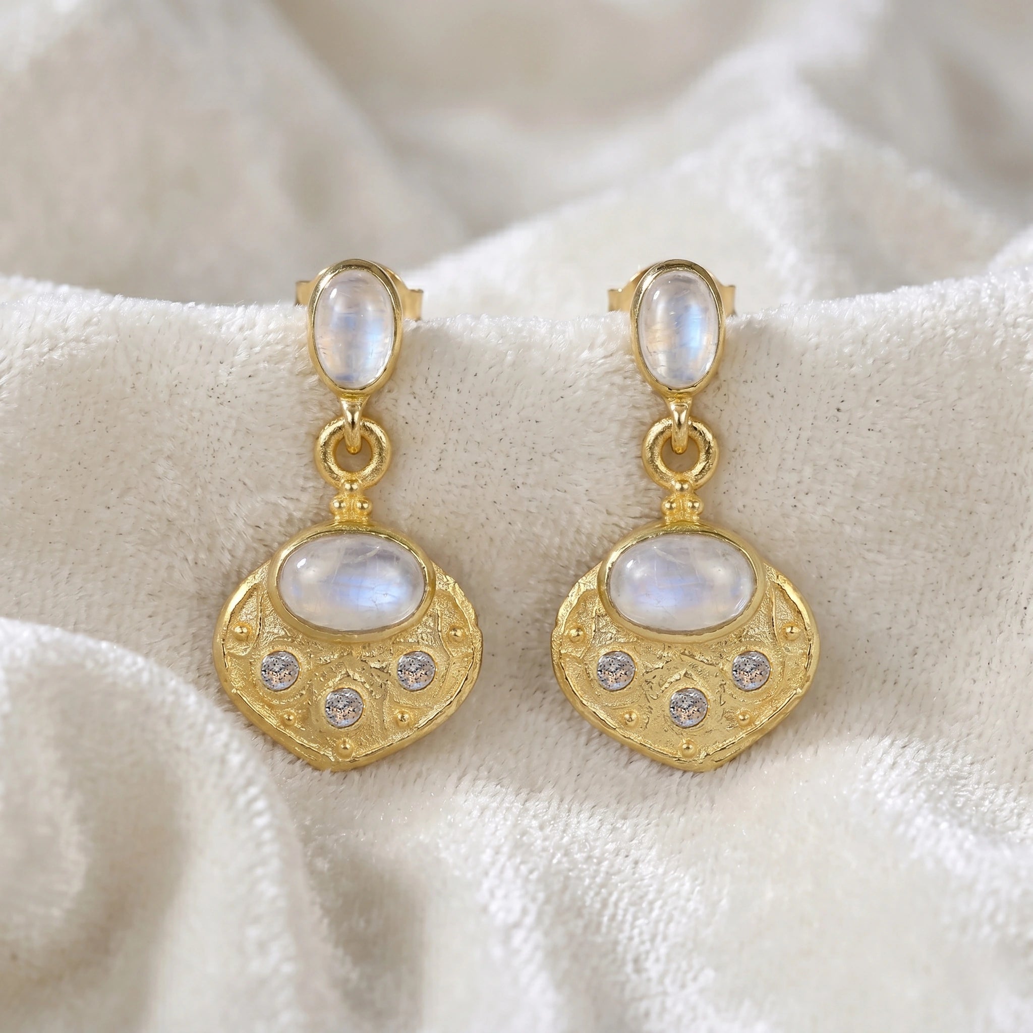 Dangle_earrings_in_gold_plated_silver_with_moonstone_and_labradorite_shown_at_front_angle_view_on_soft_velvet_fabric_background