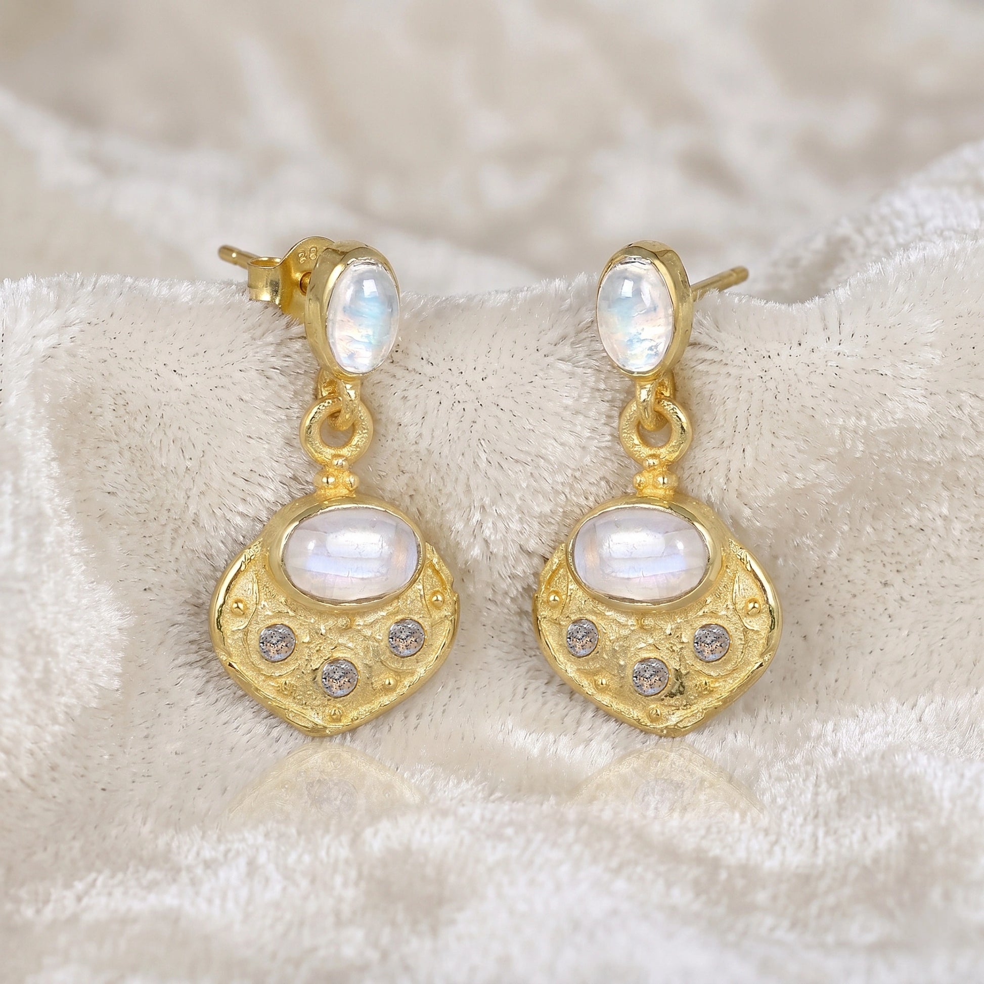 Dangle_earrings_in_gold_plated_silver_with_moonstone_and_labradorite_shown_at_slightly_angled_on_soft_velvet_fabric_background