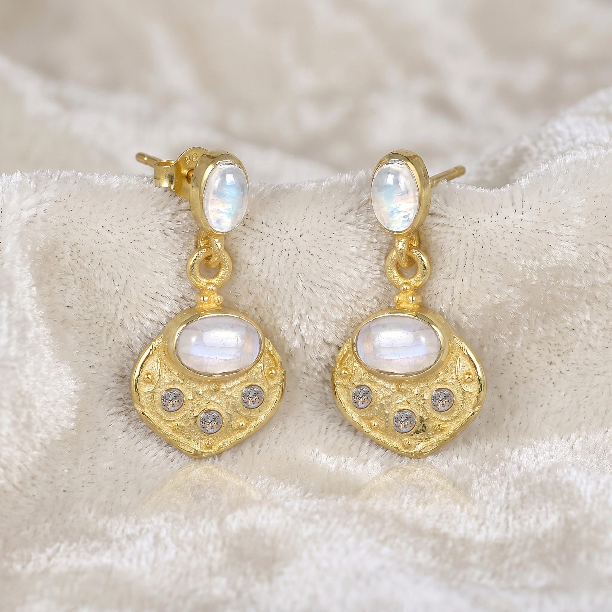 Dangle_earrings_in_gold_plated_silver_with_moonstone_and_labradorite_shown_at_slightly_angled_on_soft_velvet_fabric_background