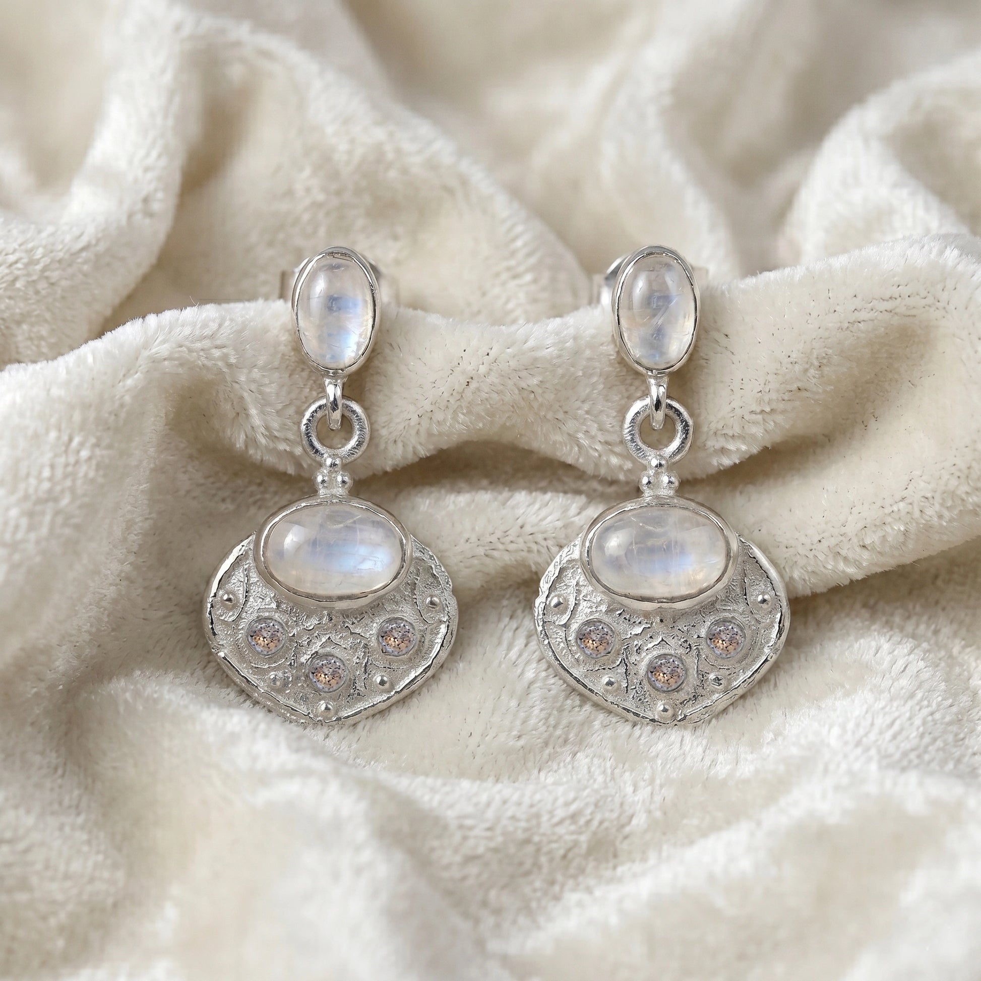Dangle_earrings_in_sterling_silver_with_moonstone_and_labradorite_shown_at_front_angle_on_soft_velvet_fabric_background