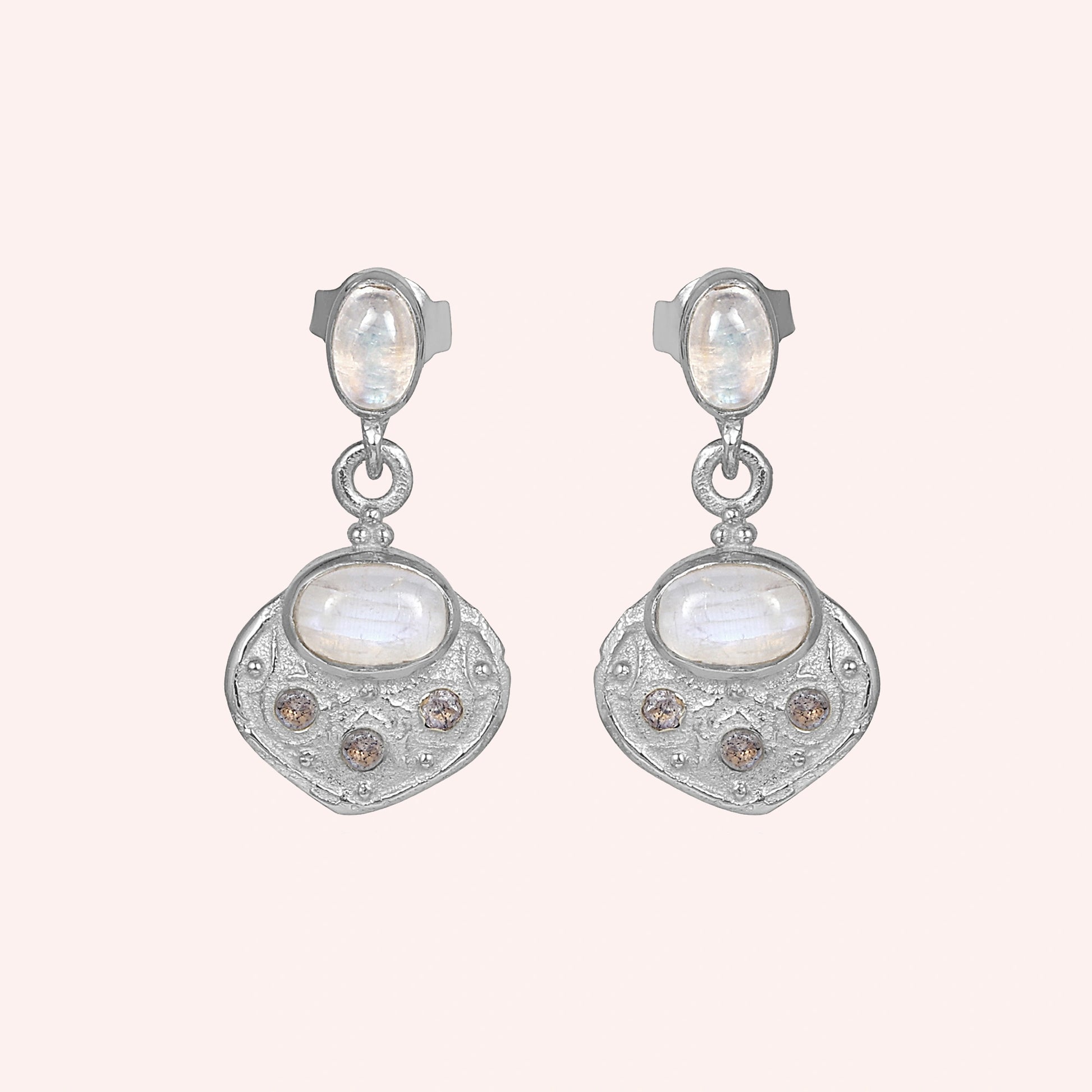 Dangle_earrings_in_sterling_silver_with_moonstone_and_labradorite_shown_at_front_angle_on_solid_pink_background