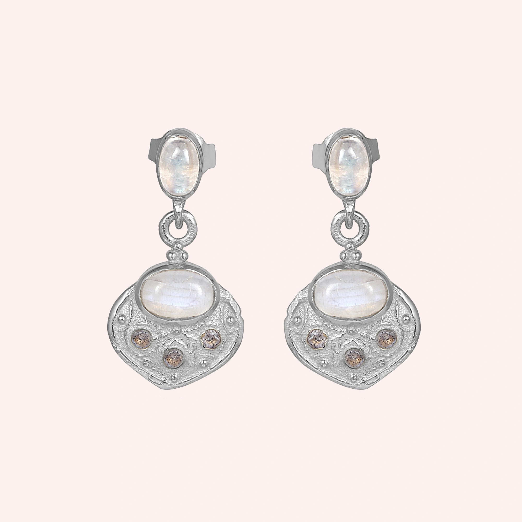 Dangle_earrings_in_sterling_silver_with_moonstone_and_labradorite_shown_at_front_angle_on_solid_pink_background