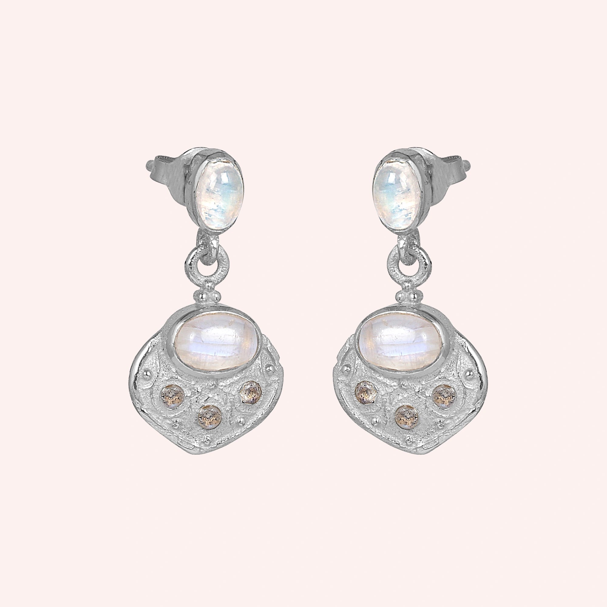 Dangle_earrings_in_sterling_silver_with_moonstone_and_labradorite_shown_at_slightly_angled_on_solid_pink_background