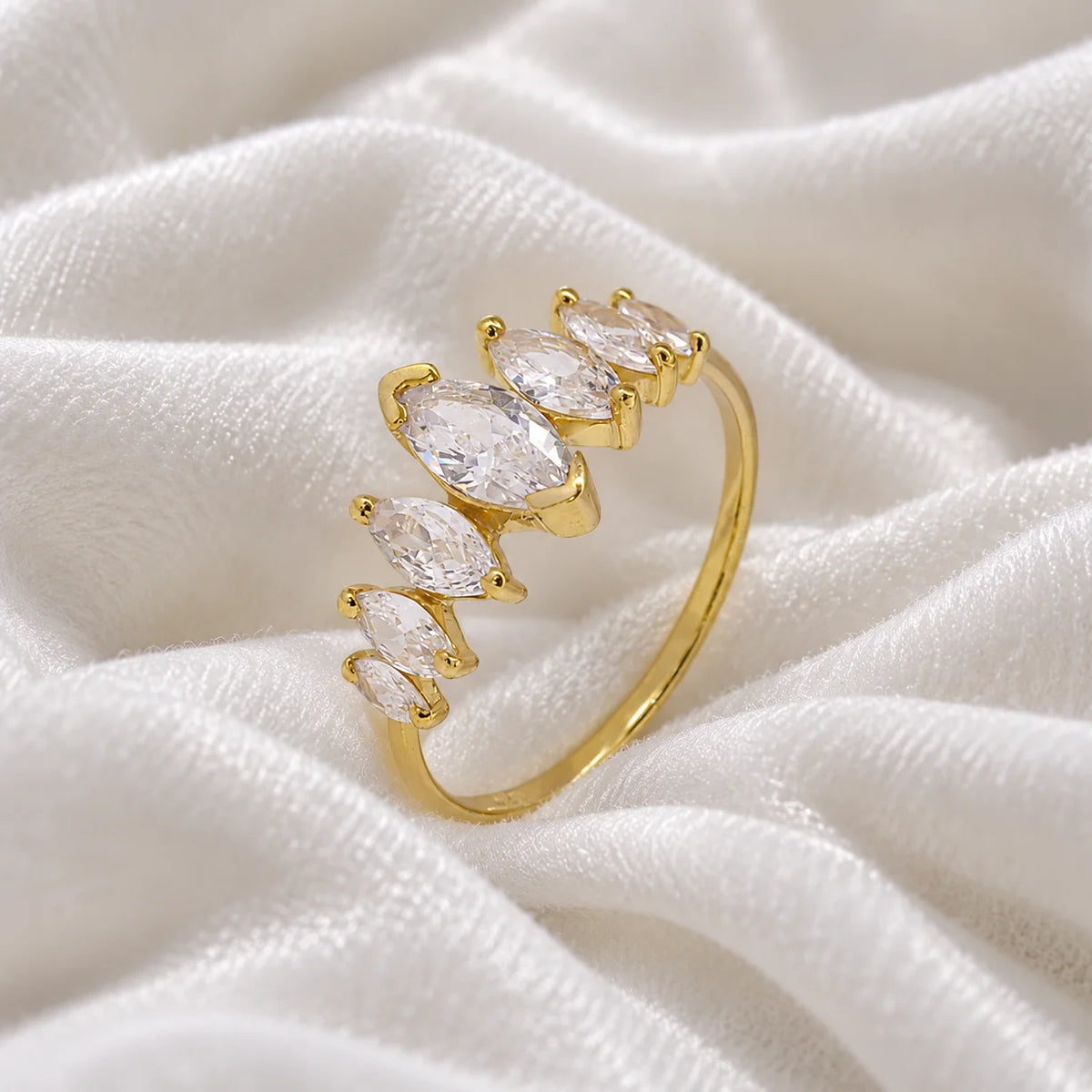 Designer_ring_in_gold_plated_silver_with_marquise_cut_CZ_stones_at_side_angle_view_on_soft_fabric_background