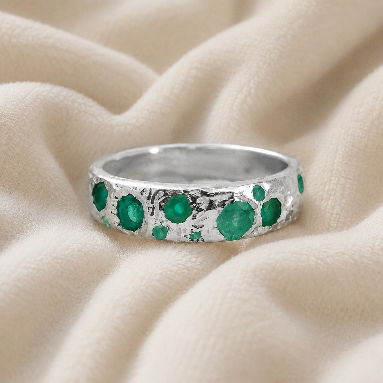 Designer_ring_in_sterling_silver_with_multiple_green_onyx_stones_at_front_angle_on_soft_fabric_background