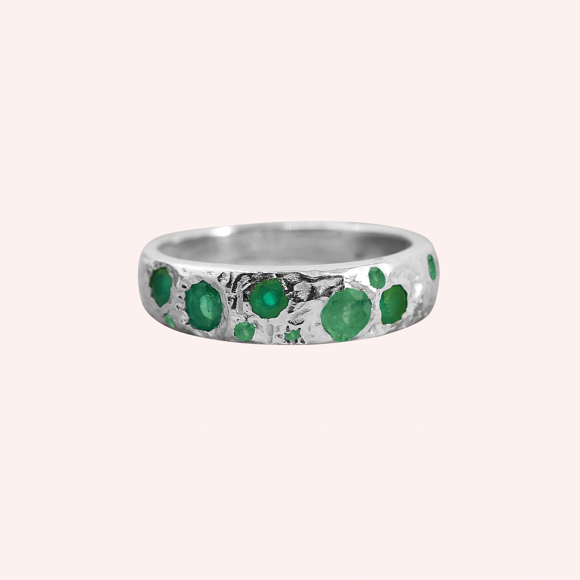 Designer_ring_in_sterling_silver_with_multiple_green_onyx_stones_at_front_angle_on_solid_pink_background