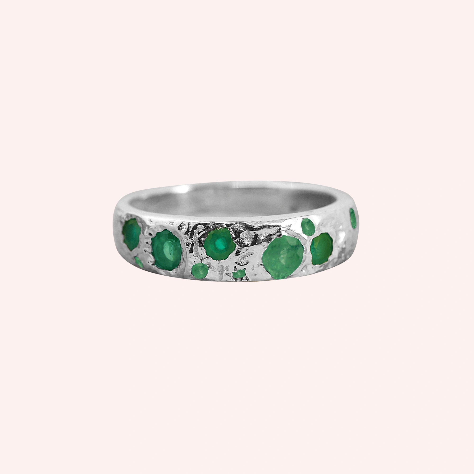 Designer_ring_in_sterling_silver_with_multiple_green_onyx_stones_at_front_angle_on_solid_pink_background