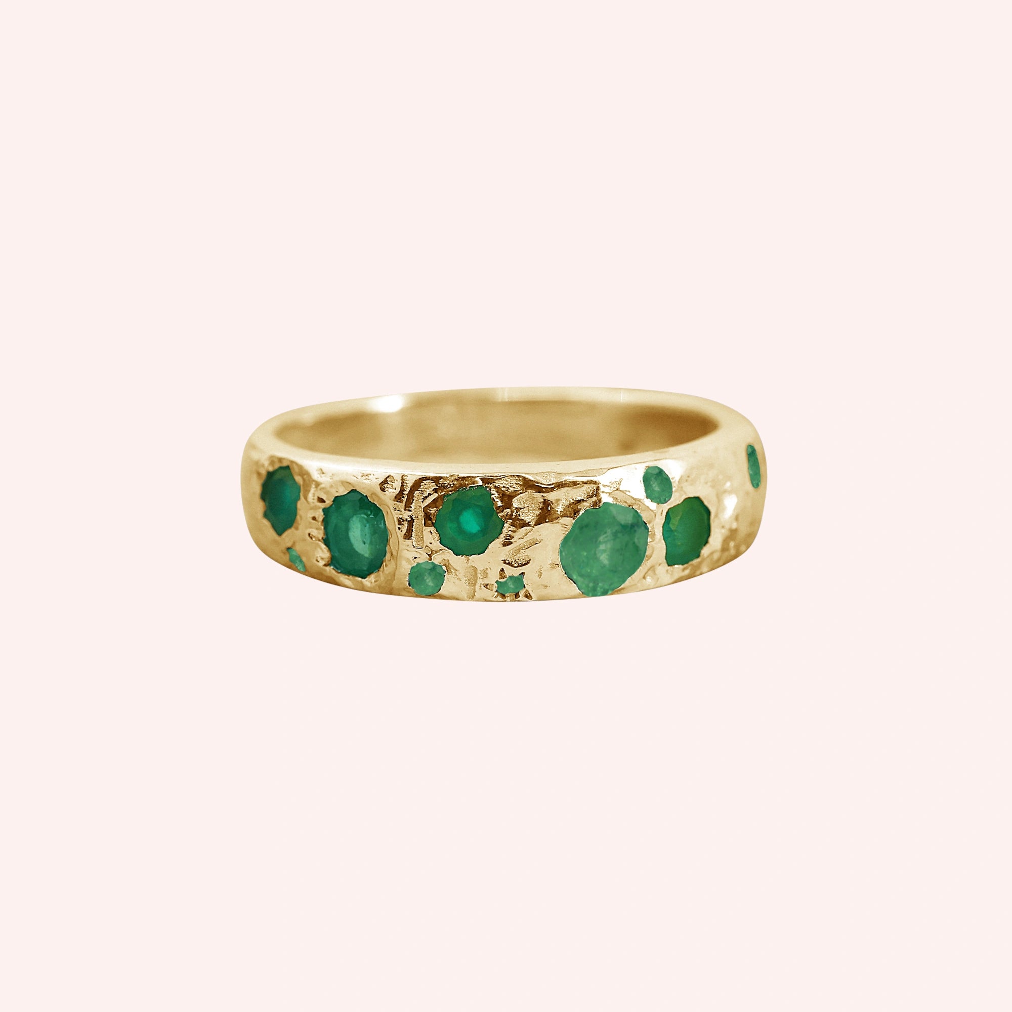 Designer_ring_in_gold_plated_silver_with_multiple_green_onyx_stones_at_front_angle_on_solid_pink_background