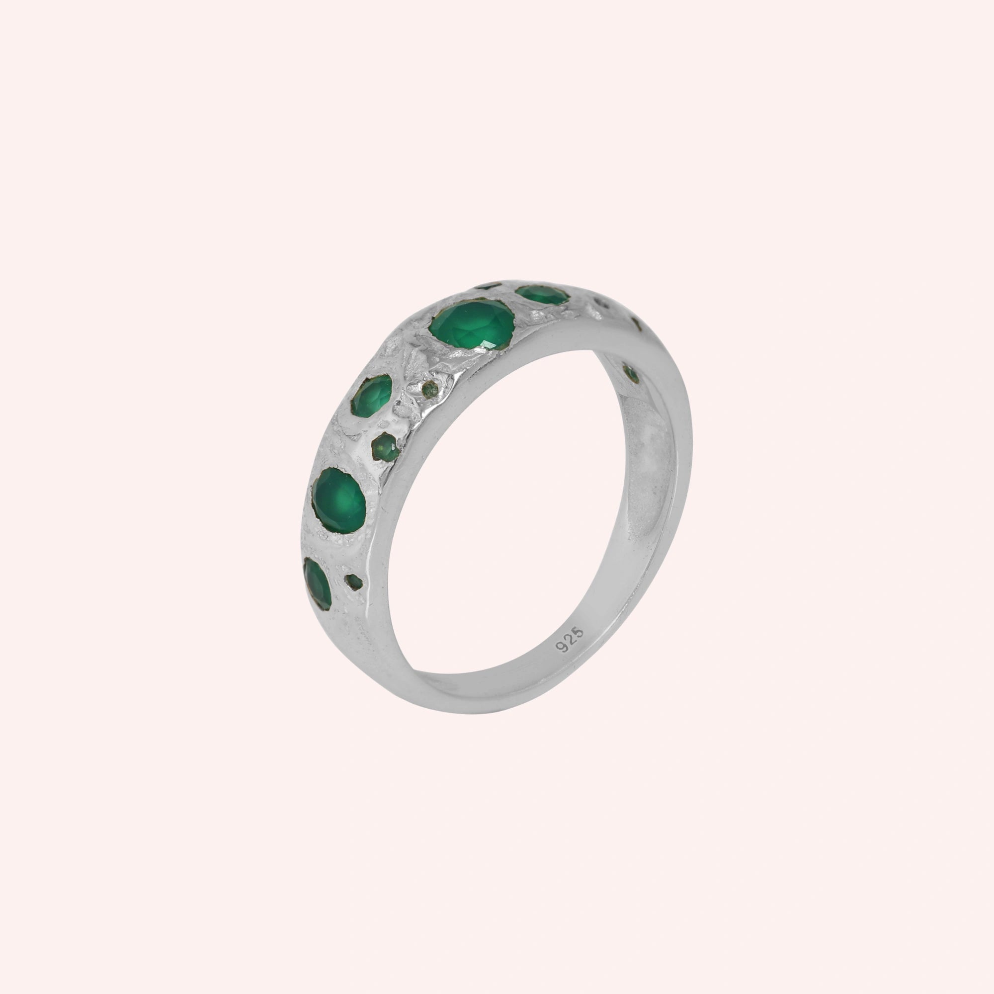 Designer_ring_in_sterling_silver_with_multiple_green_onyx_stones_at_slight_angle_on_solid_pink_background