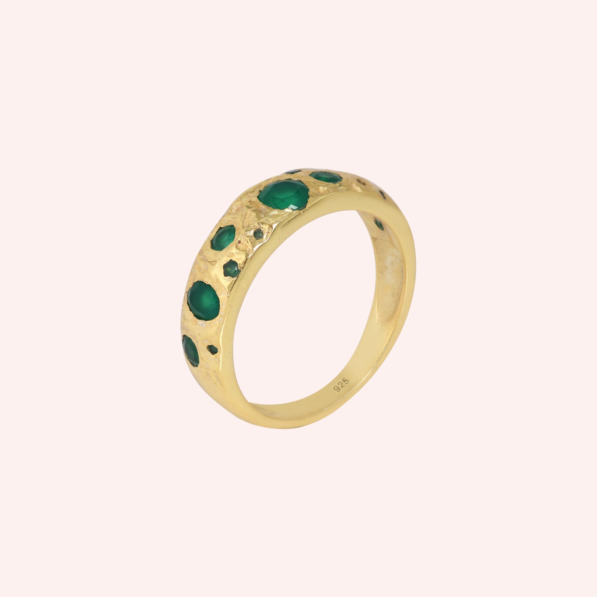 Designer_ring_in_gold_plated_silver_with_multiple_green_onyx_stones_at_slight_angle_on_solid_pink_background