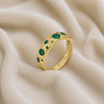 Designer_ring_in_gold_plated_silver_with_multiple_green_onyx_stones_at_slight_angle_on_soft_fabric_background
