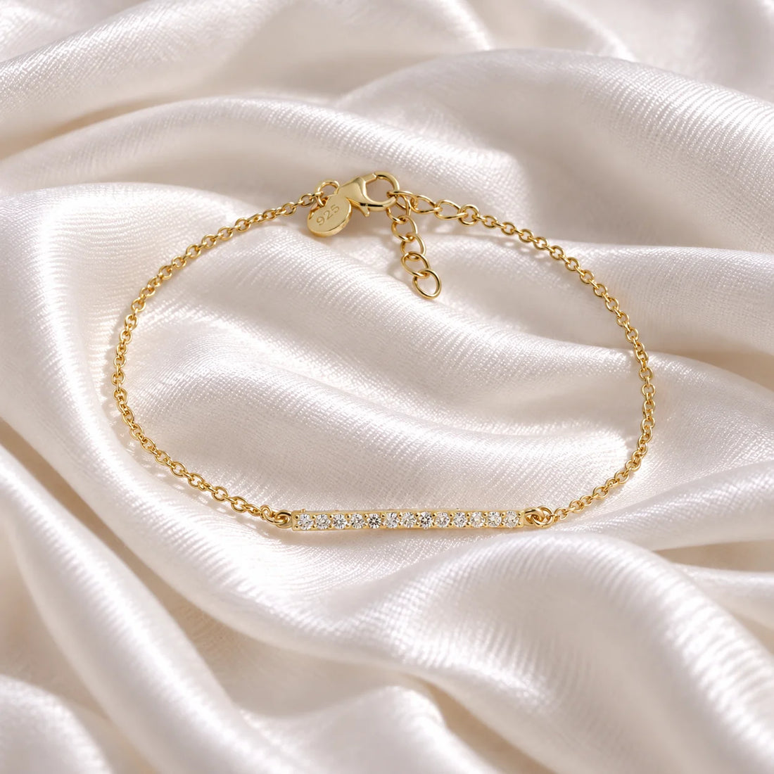 Diamond_bracelet_in_gold_plated_silver_with_a_bar_design_at_front_angle_view_on_soft_fabric_background