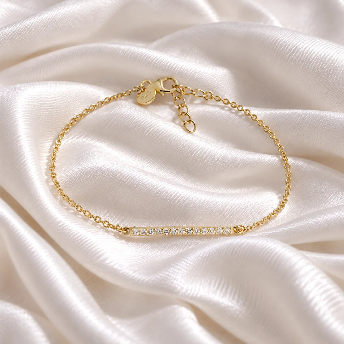 Diamond_bracelet_in_gold_plated_silver_with_a_bar_design_at_front_angle_view_on_soft_fabric_background